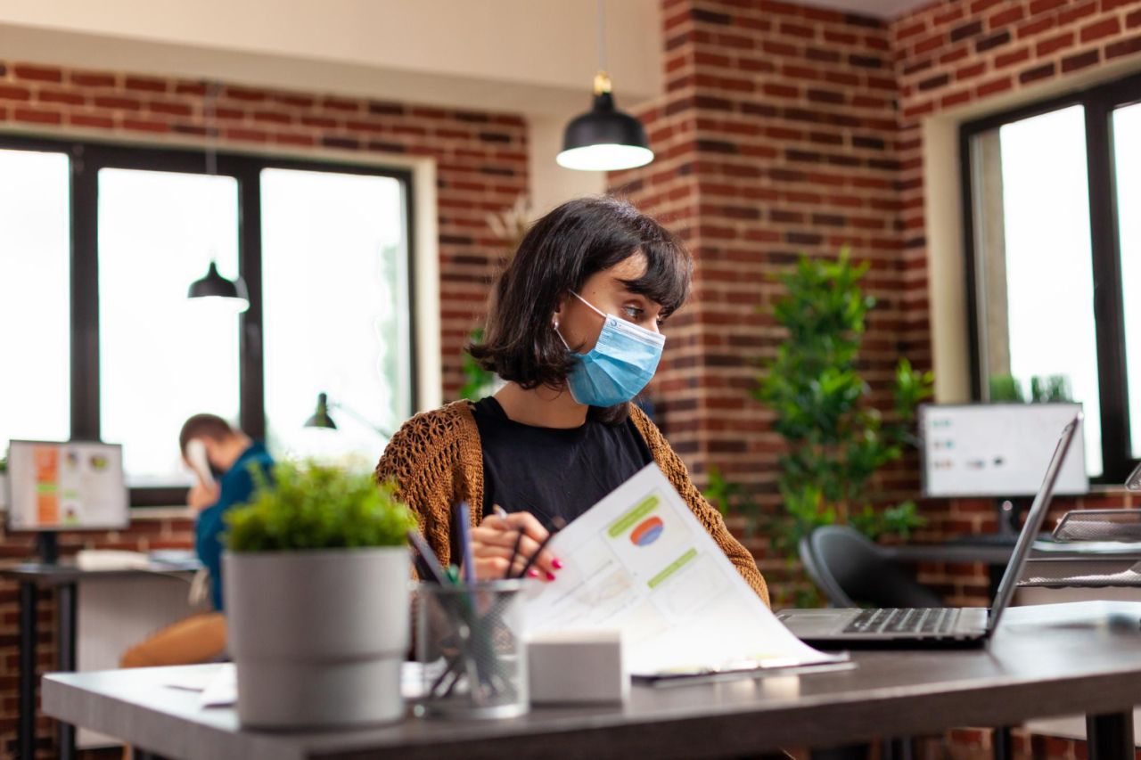 executive-manager-with-medical-protection-face-mask-prevent-infection-with-covid19-analyzing-business-graphs-typing-management-strategy-laptop-computer-businesswoman-working-project-ideas