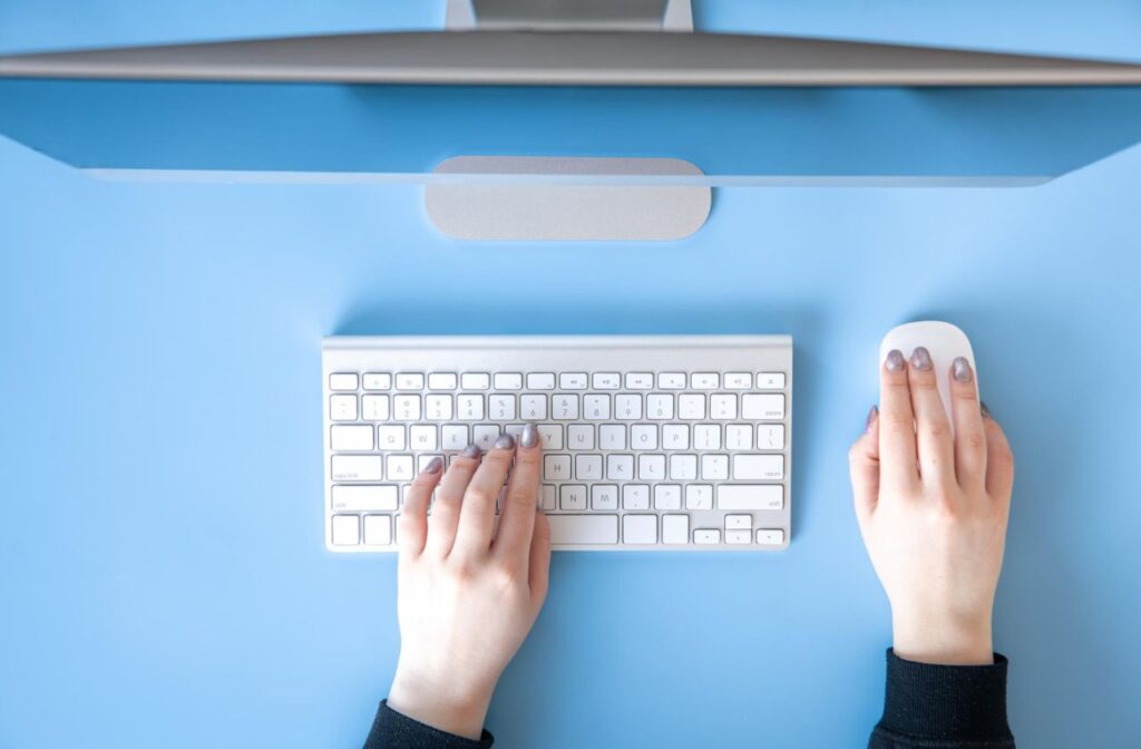 top-view-female-hands-work-computer-blue-background